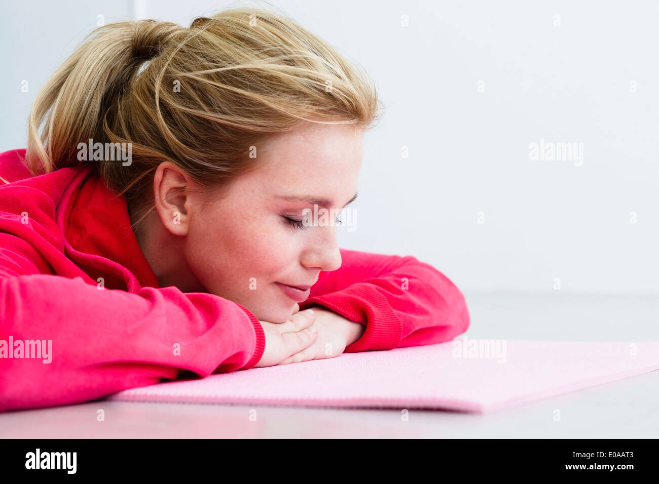 Young woman lying on exercise mat Stock Photo