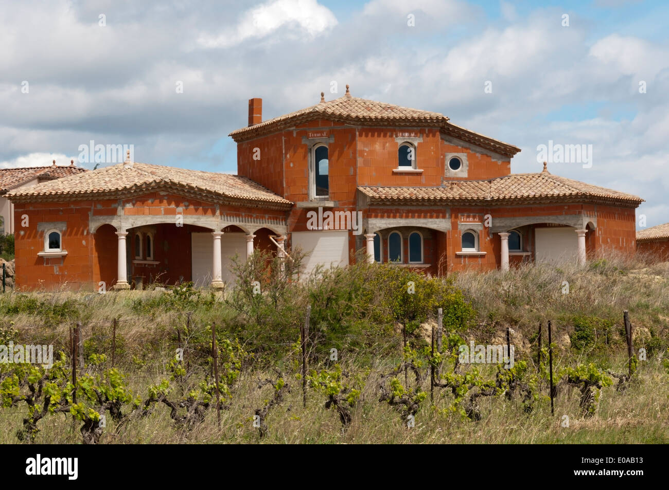 An empty unfinished villa near Magalas, Languedoc, France seen across a field of vines. Stock Photo