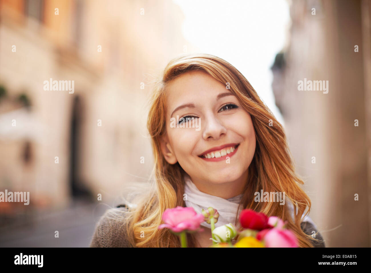 Smiling young woman with a bunch of flowers Stock Photo