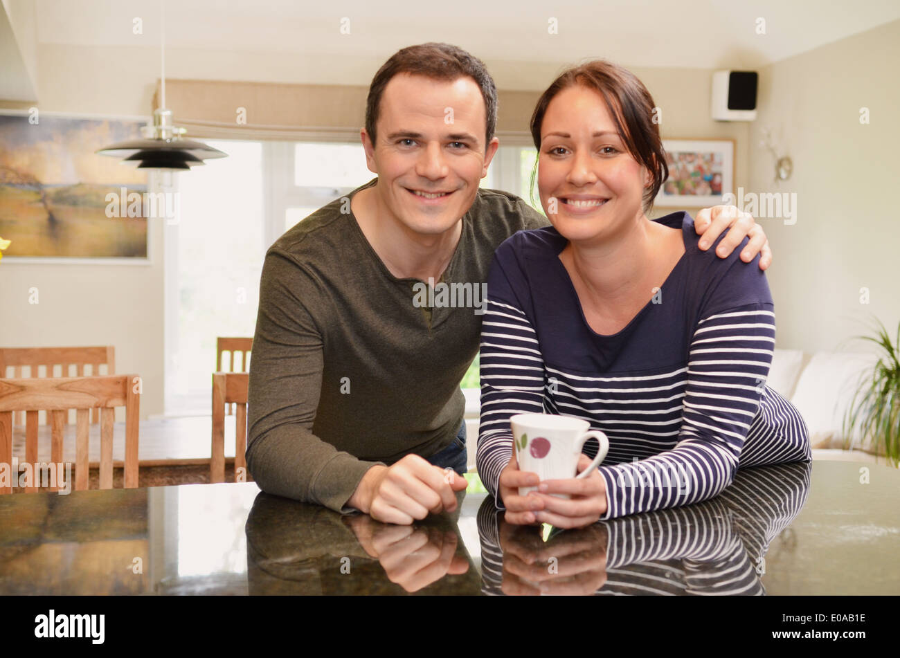 Portrait of mid adult couple leaning on kitchen counter Stock Photo