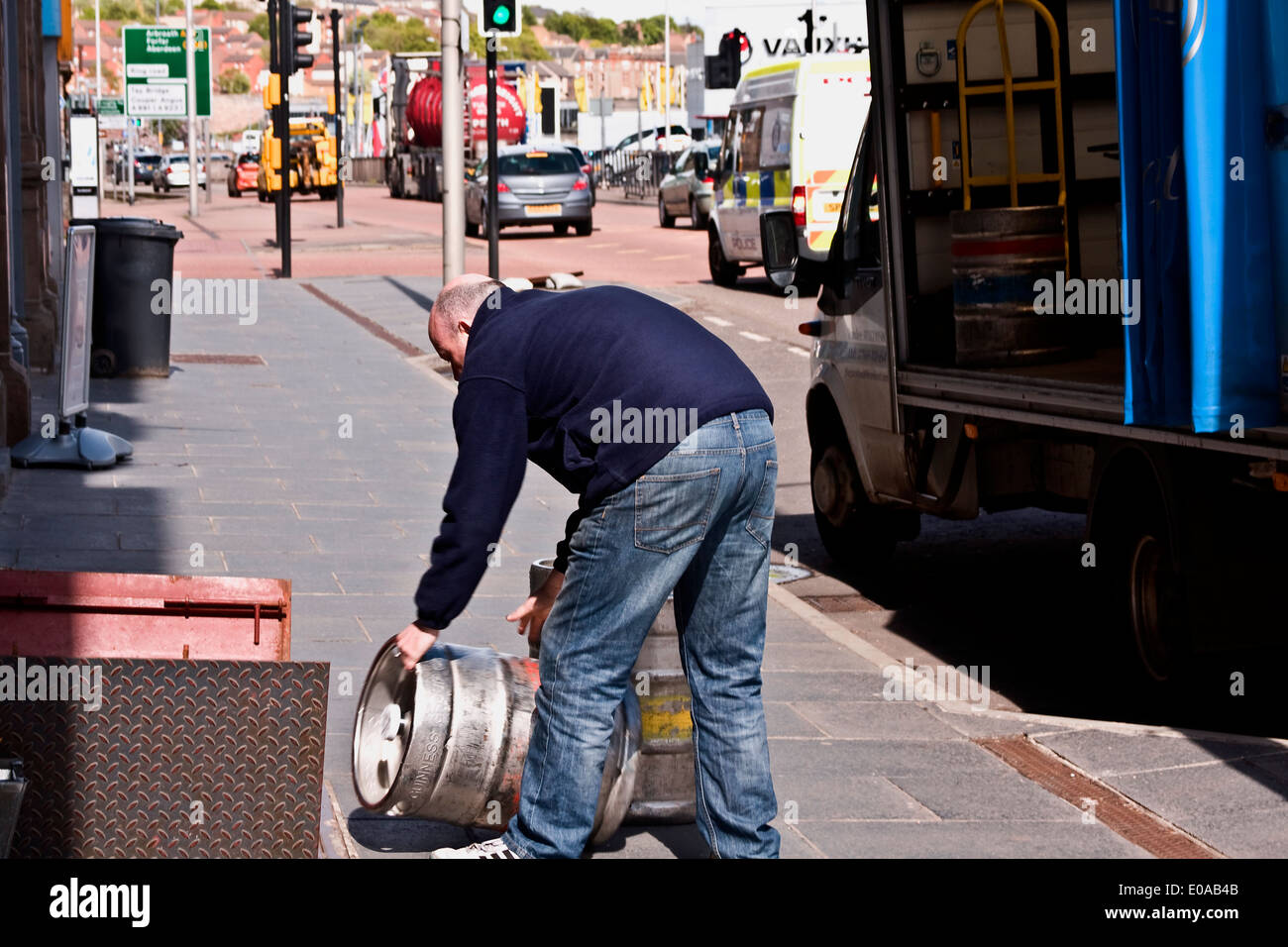 Worker unloading an aluminum Keg of Guinness Stout Ale from a delivery truck outside a Scottish pub in Dundee, UK Stock Photo