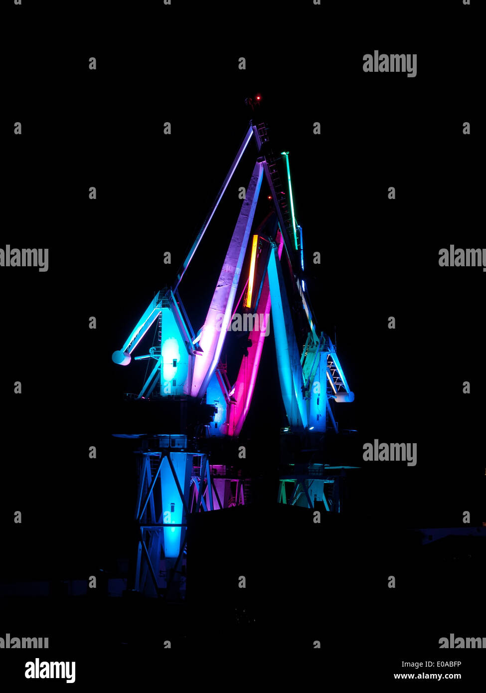 Shipyard cranes by night, multicolored illumination Stock Photo