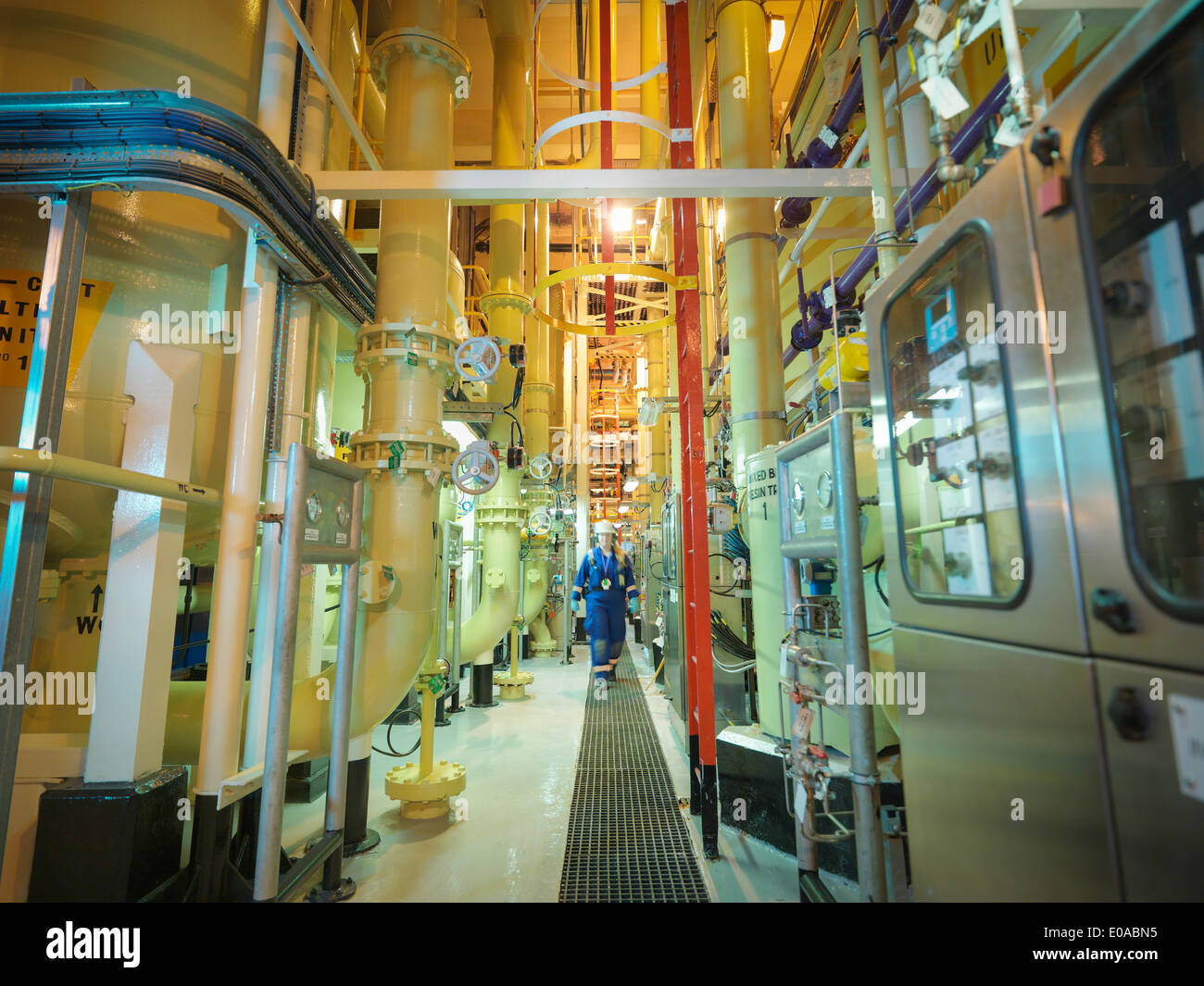 Female chemist walking amongst the pipework in power station Stock Photo