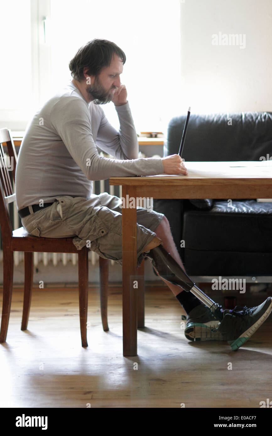 Disabled man using laptop in living room Stock Photo