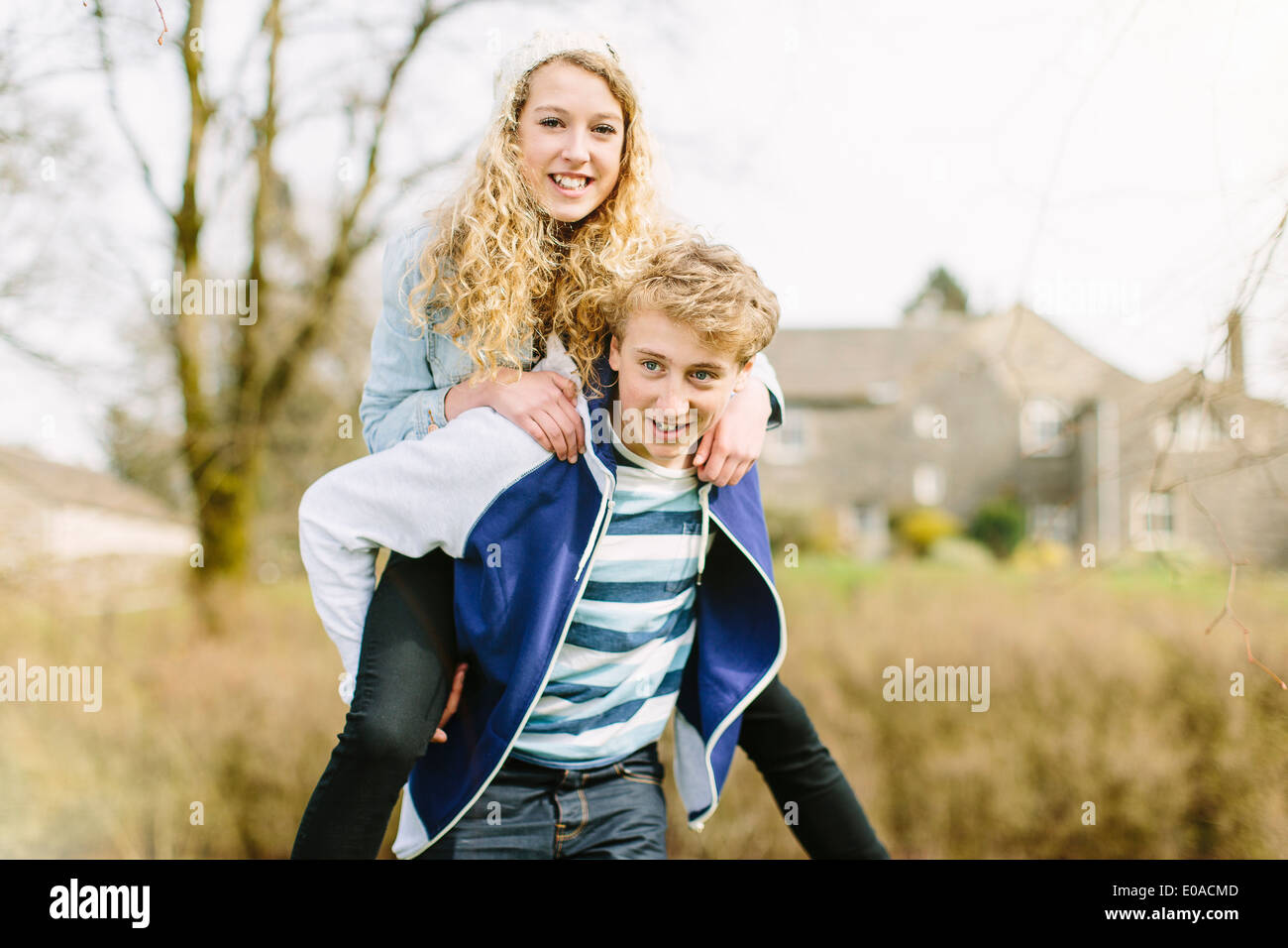 Teenage boy giving girlfriend piggyback Stock Photo