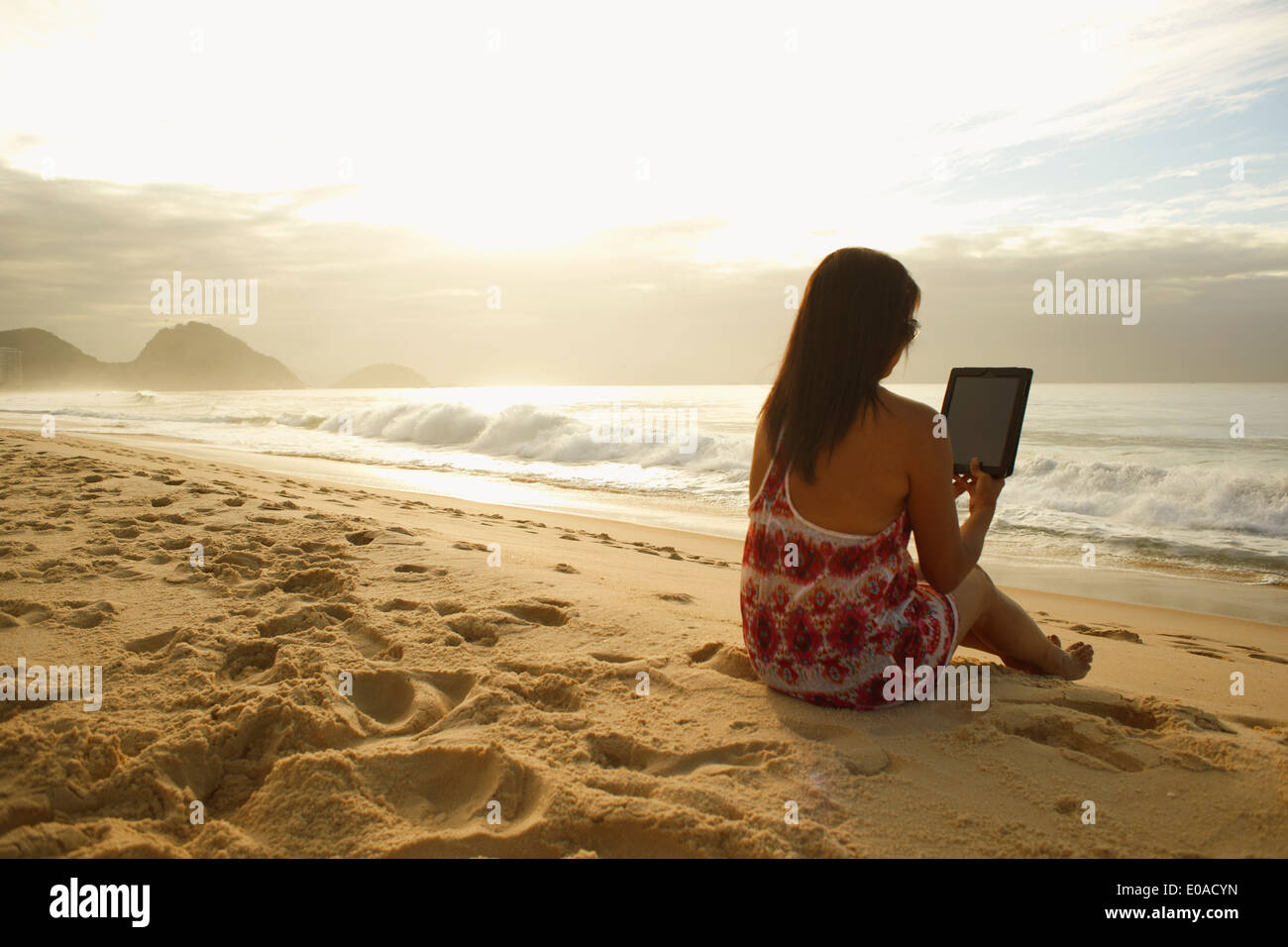 Mature woman using digital tablet on Copacabana beach, Rio De Janeiro, Brazil Stock Photo