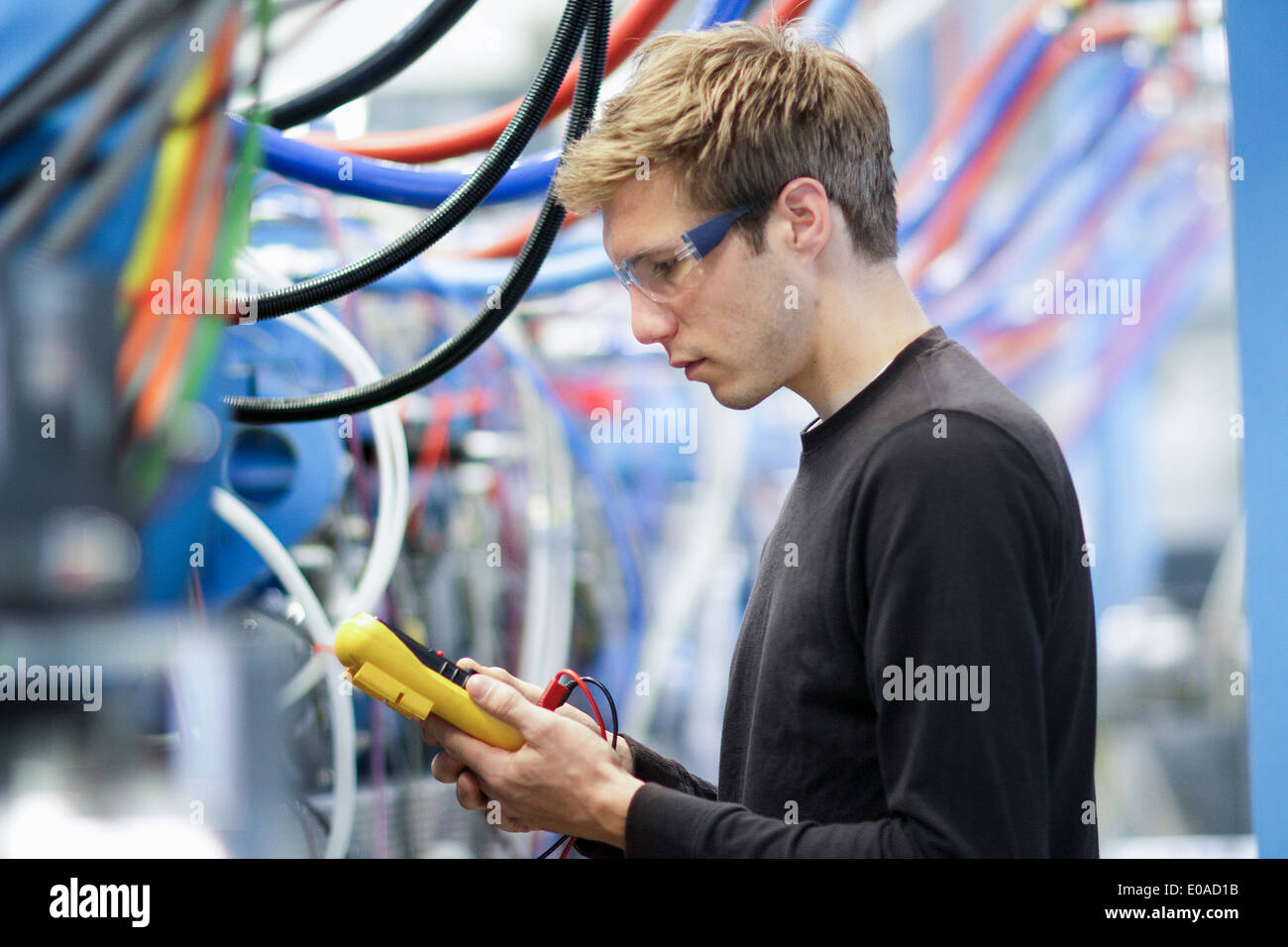 Mid adult male technician testing cables in engineering plant Stock Photo