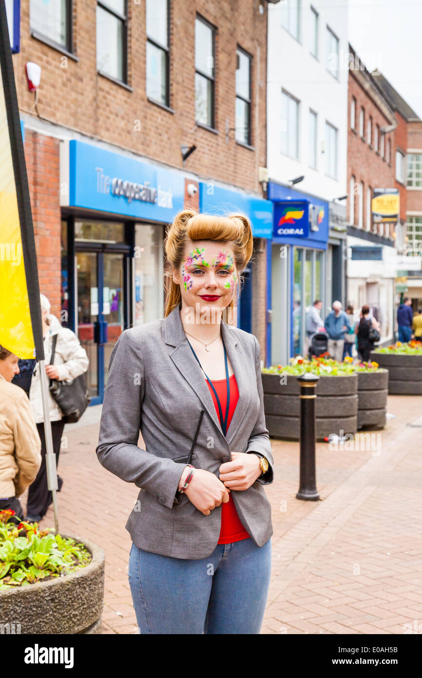 Teenage girl, with painted face, standing in the high street, smiling