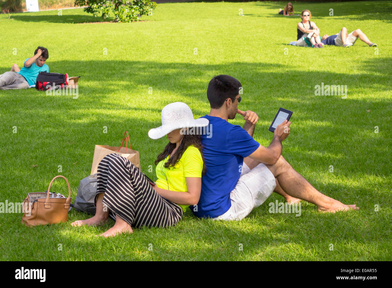 Sydney Australia,Royal Botanic Gardens,man men male,woman female women,couple,back to back,lawn,sitting,using,tablet,park,AU140309174 Stock Photo