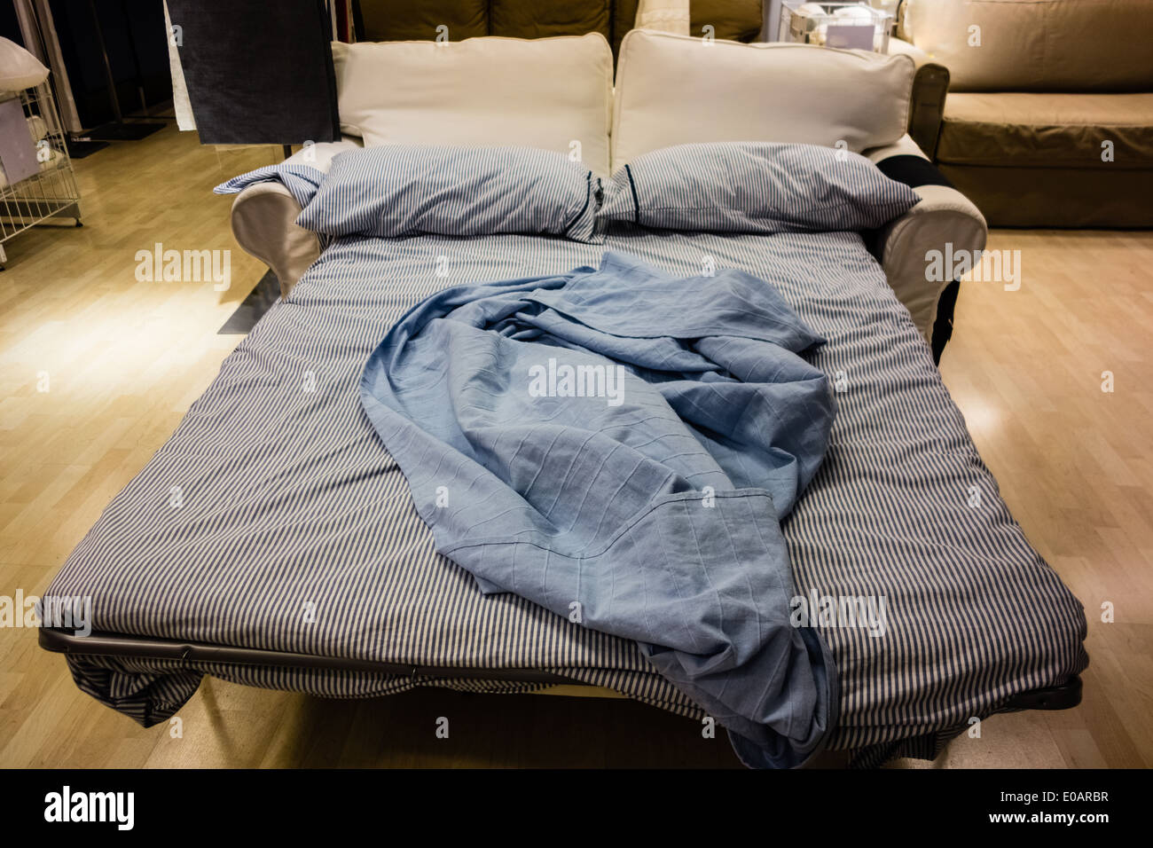 an opened sofa bed with bed clothes and pillows Stock Photo