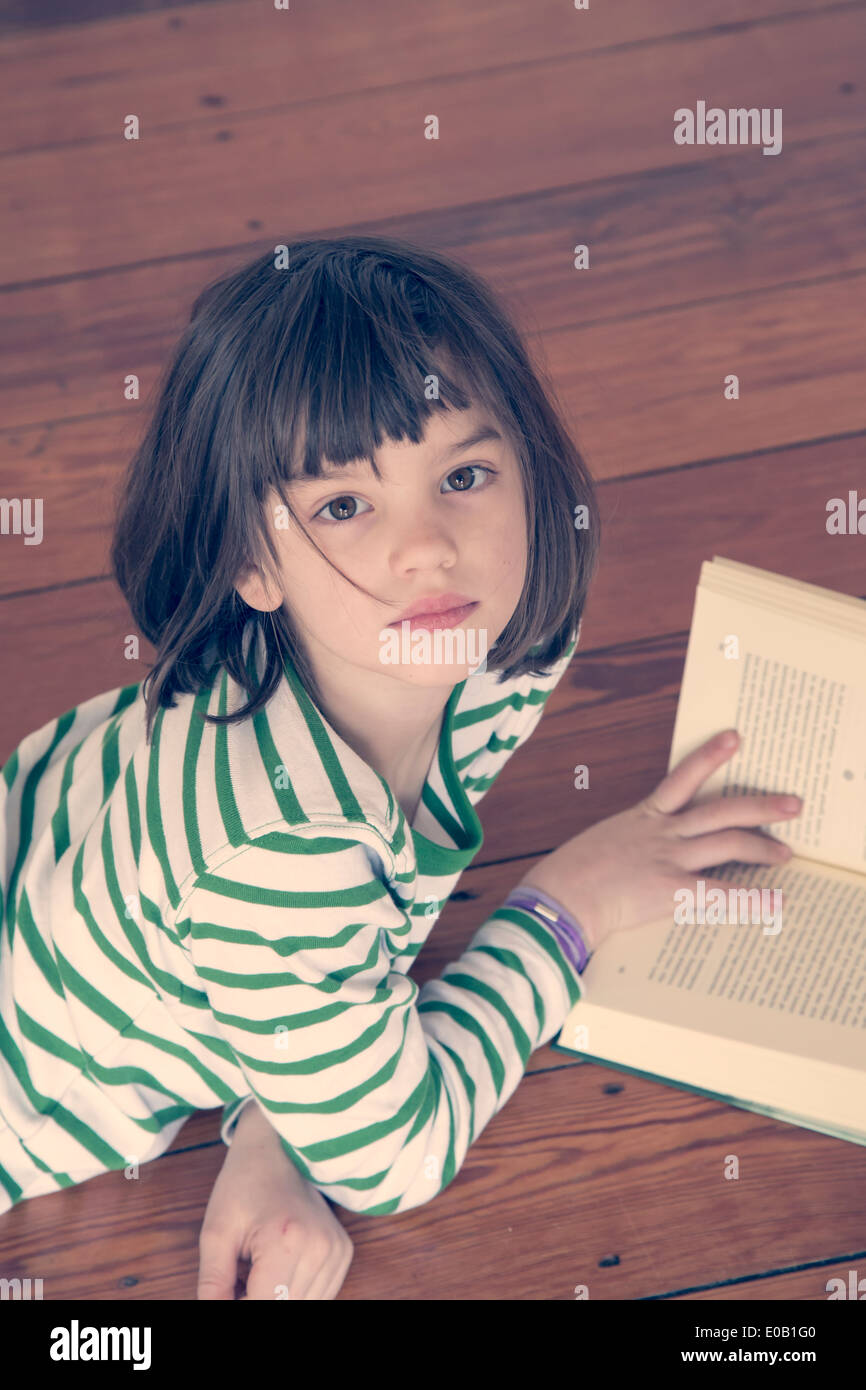 Portrait of little girl reading book at home Stock Photo - Alamy