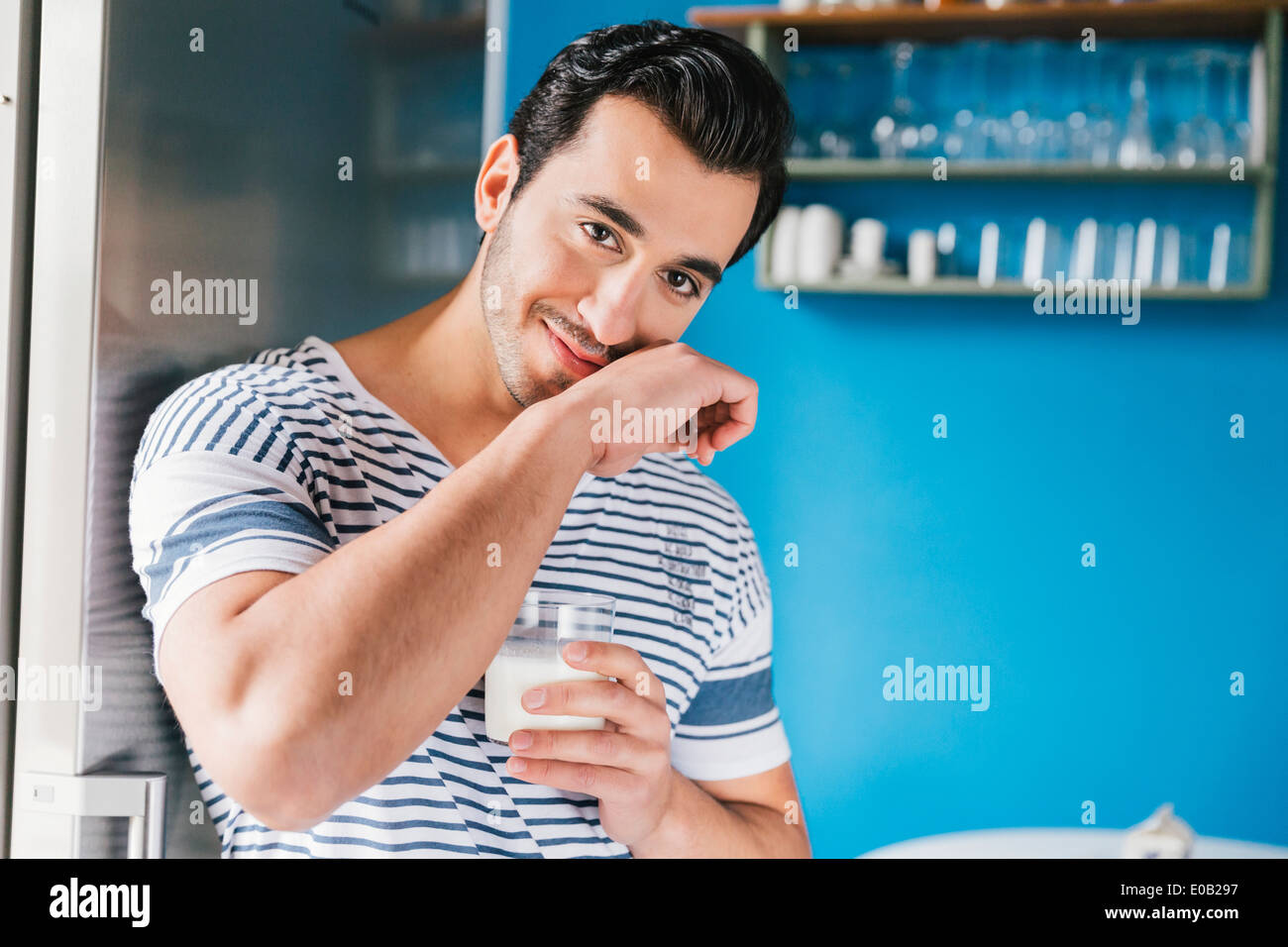 Portrait of smiling young man wiping off his milk moustache Stock Photo