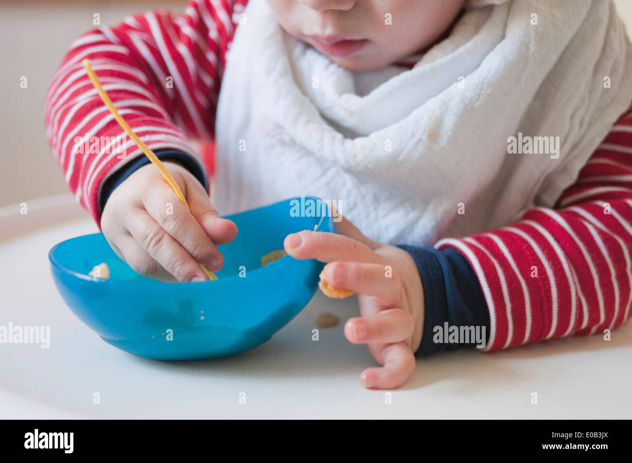 Germany, Baby boy eating from plastic bowl Stock Photo