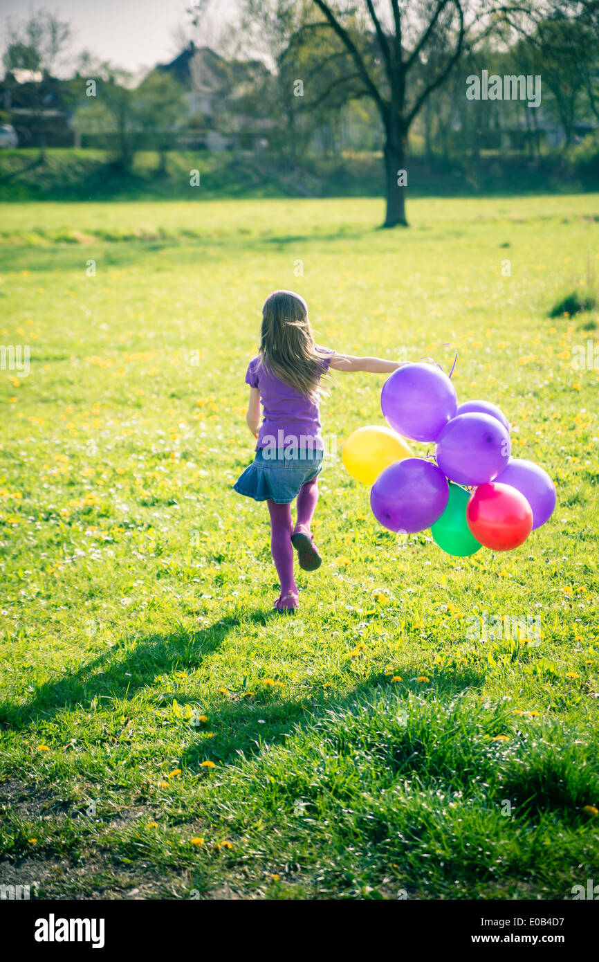 Little girl with balloons running on a meadow Stock Photo Alamy