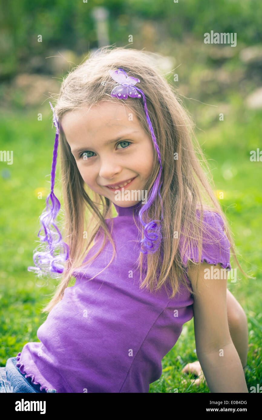 Portrait of smiling little girl sitting in the garden Stock Photo - Alamy