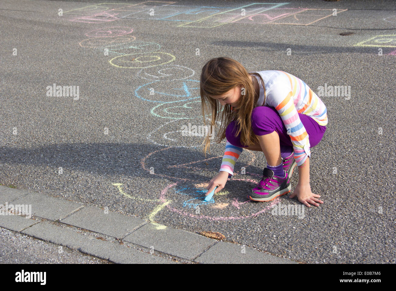 Girl drawing with coloured crayon on asphalt Stock Photo