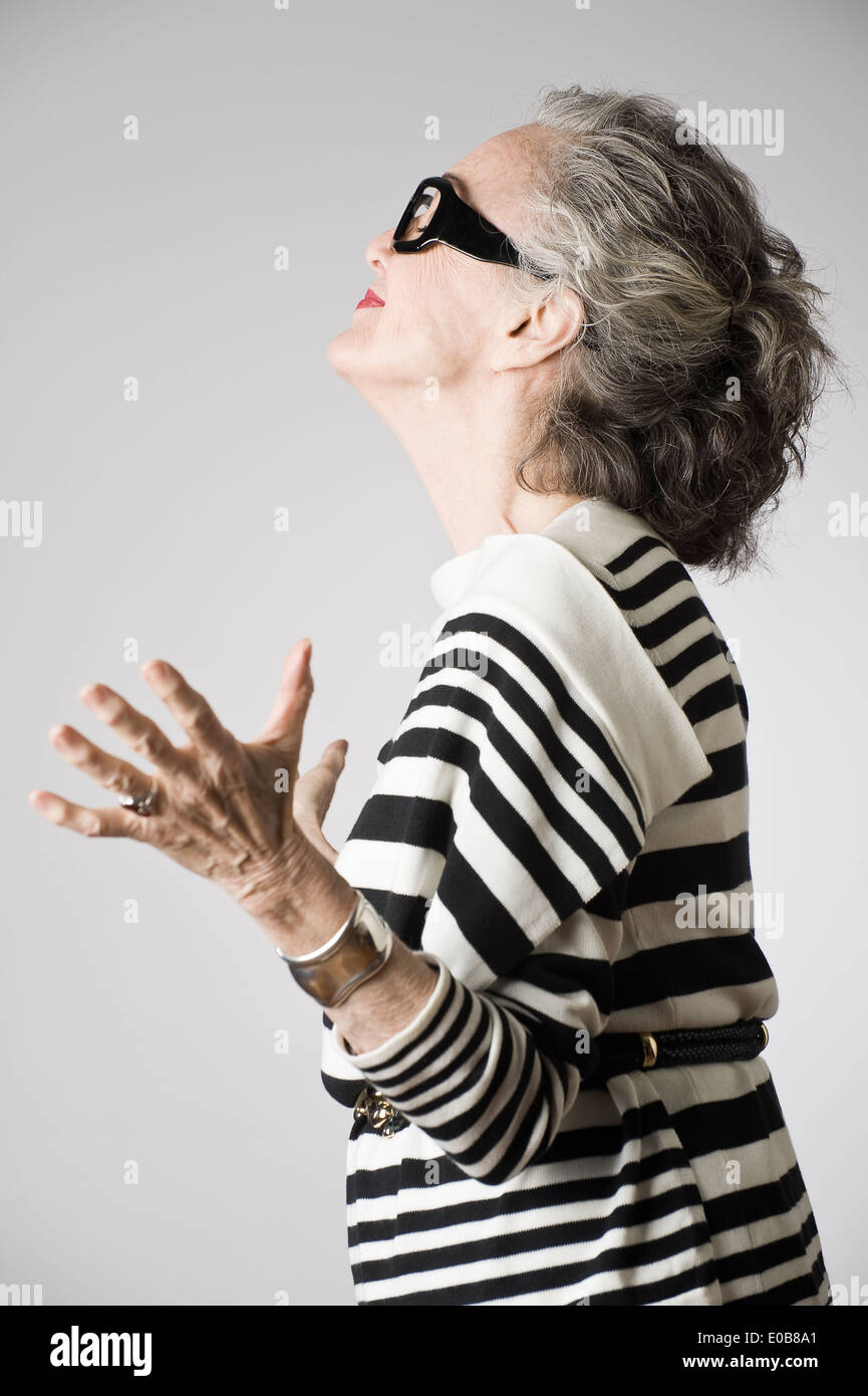 Portrait of senior woman, arms open, side view Stock Photo