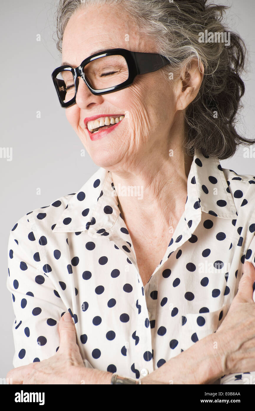 Portrait of senior woman, arms crossed, laughing Stock Photo
