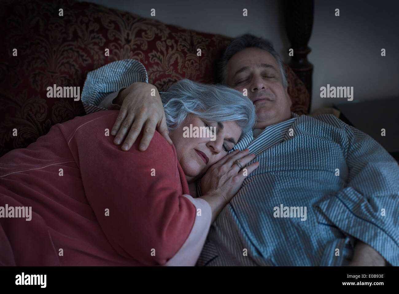 Affectionate mature adult couple sleeping on bed Stock Photo