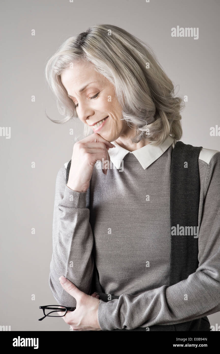 Mature woman with hand on chin, smiling Stock Photo