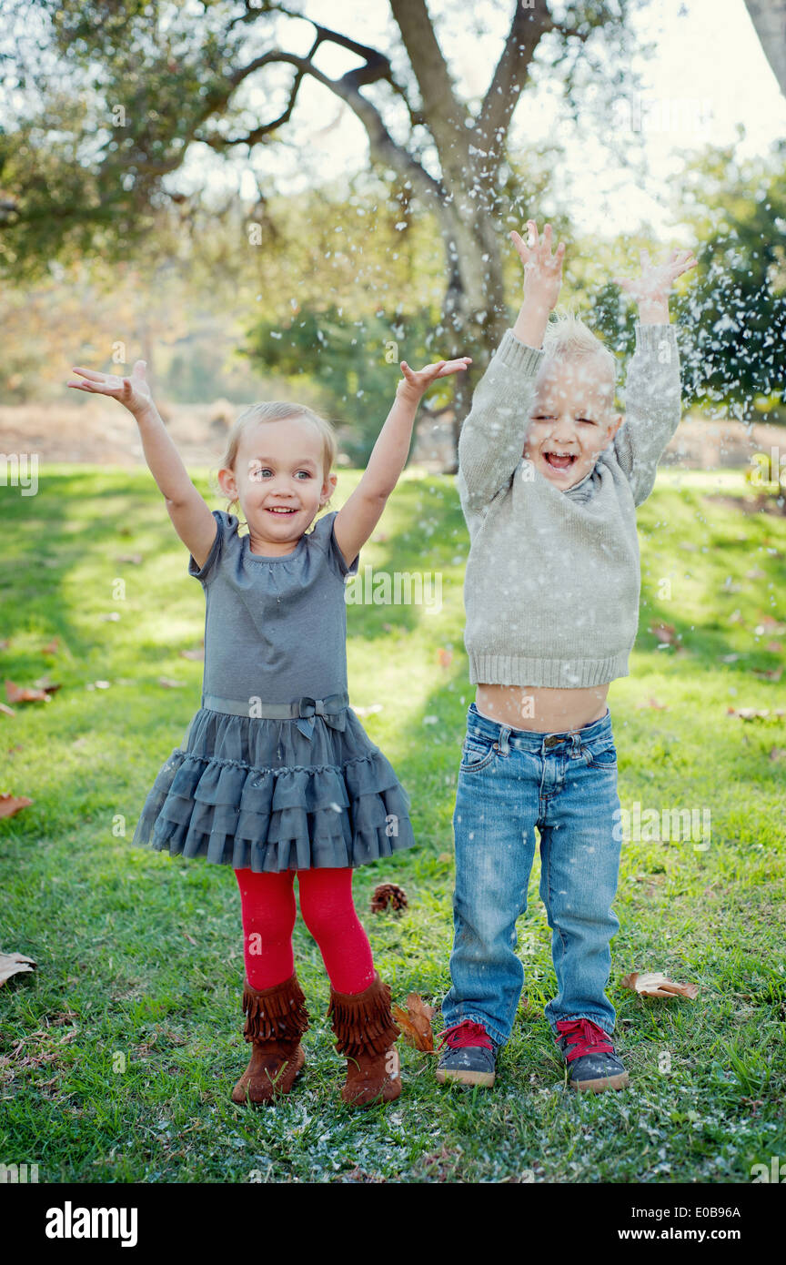 Brother and sister with arms raised, in garden Stock Photo Alamy
