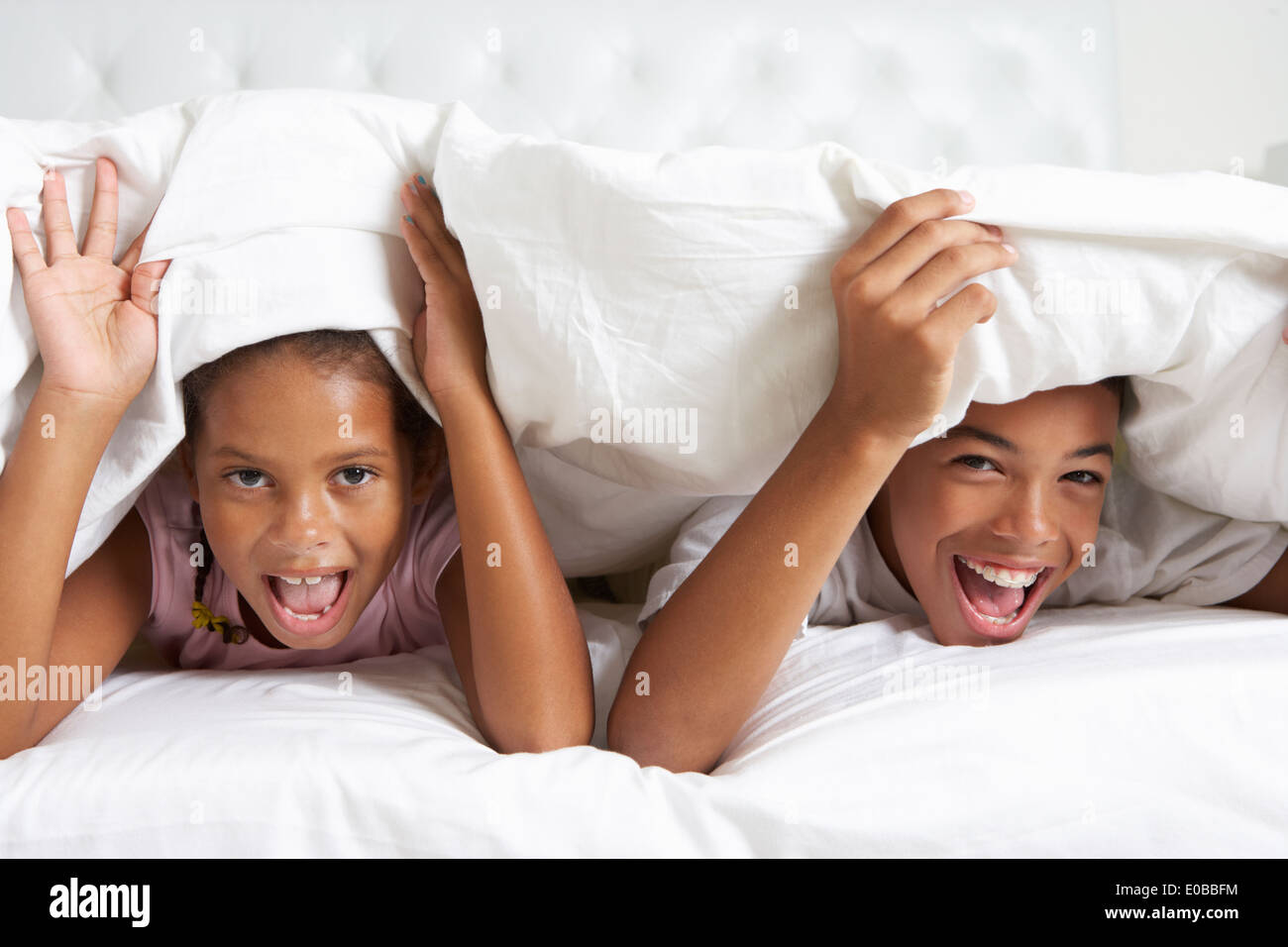 Two Children Hiding Under Duvet In Bed Stock Photo Alamy