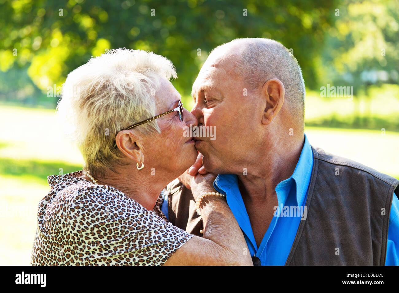 older senior citizens in love pair kiss each other. Outside., aelteres verliebtes Senioren Paar kuesst sich. Im Freien. Stock Photo