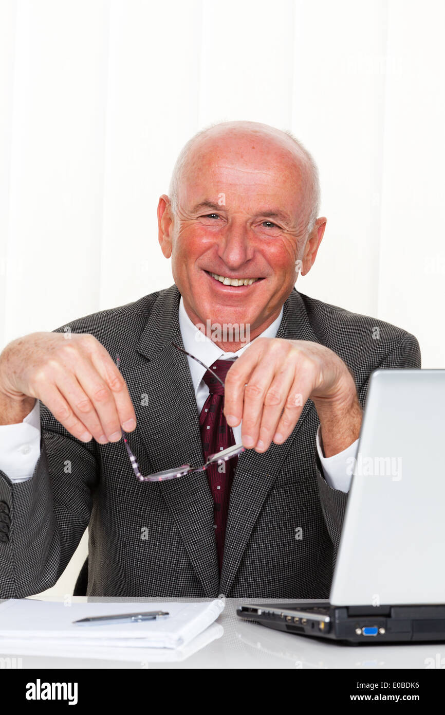 A successful older enterpriser sits in his office with laptop Stock Photo
