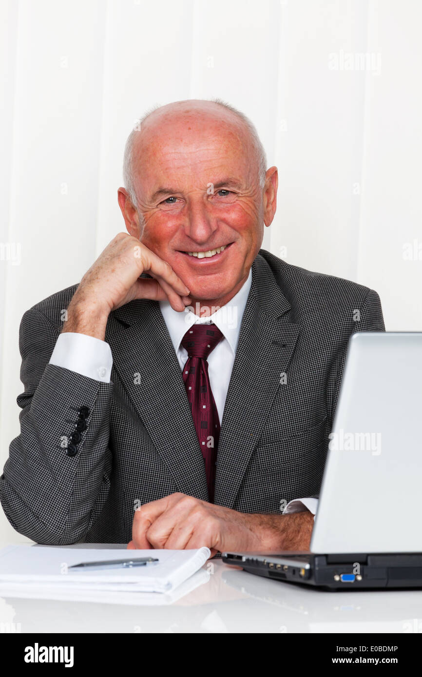 A successful older enterpriser sits in his office with laptop Stock Photo