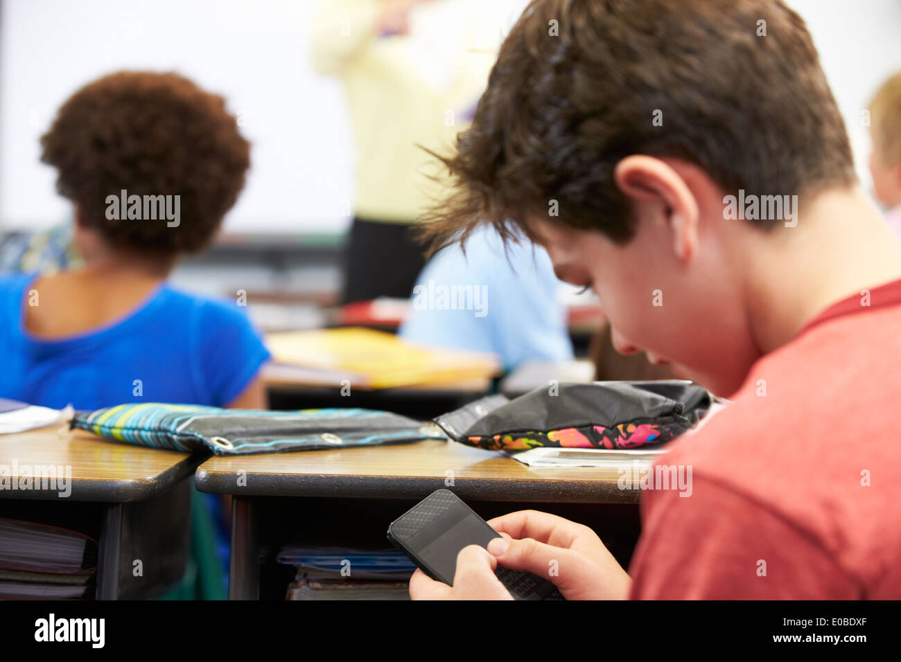 Pupil Sending Text Message On Mobile Phone In Class Stock Photo