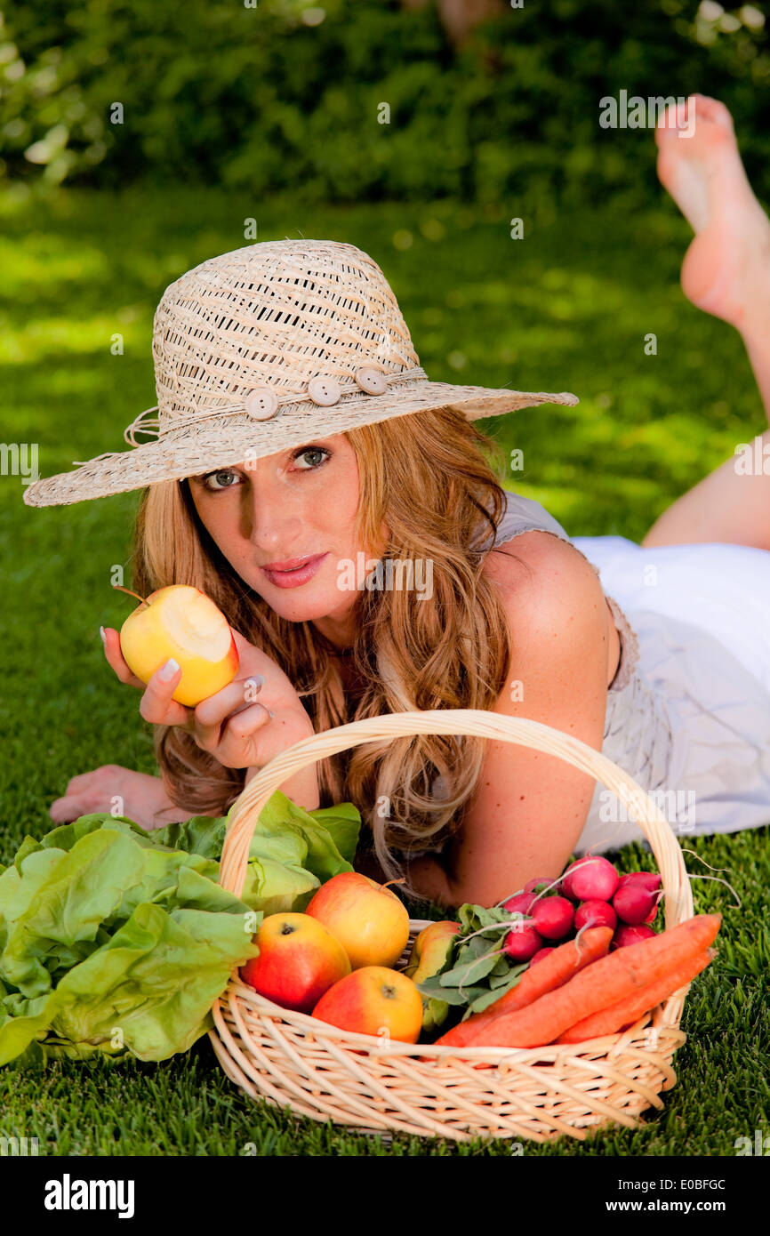 Fruit and vegetables in the basket. Woman carries a solar hat, Obst und Gemuese im Korb. Frau traegt einen Sonnenhut Stock Photo