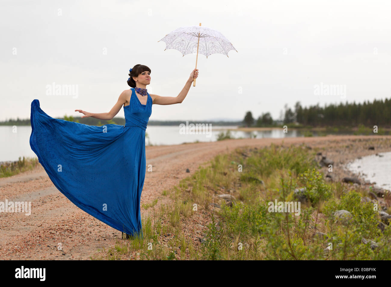 girl tries to keep a umbrella which pulls out a wind from her hands. Stock Photo