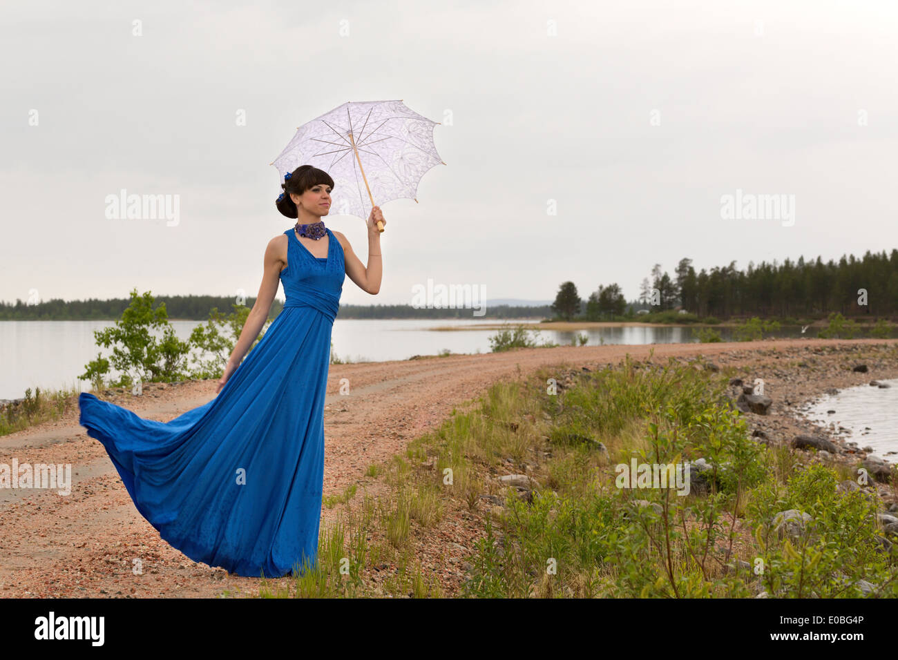 A girl tries to keep a umbrella which pulls out a wind from her hands. Stock Photo