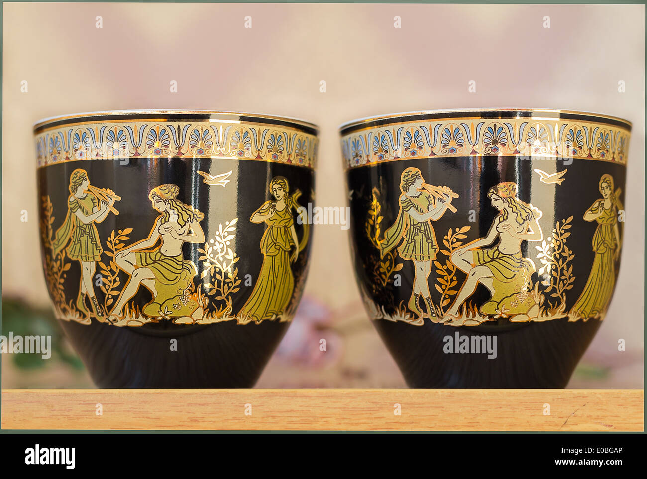 The beautiful tea cups decorated with a list with gold with the image of scenes from antique life. Stock Photo