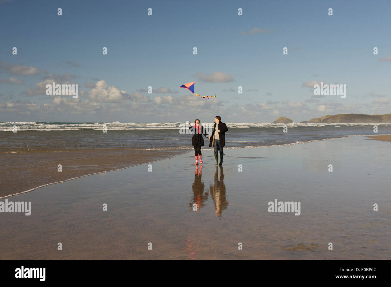 Young Romantic Couple Flying a Kite on a Beautiful Cornish Beach Stock Photo