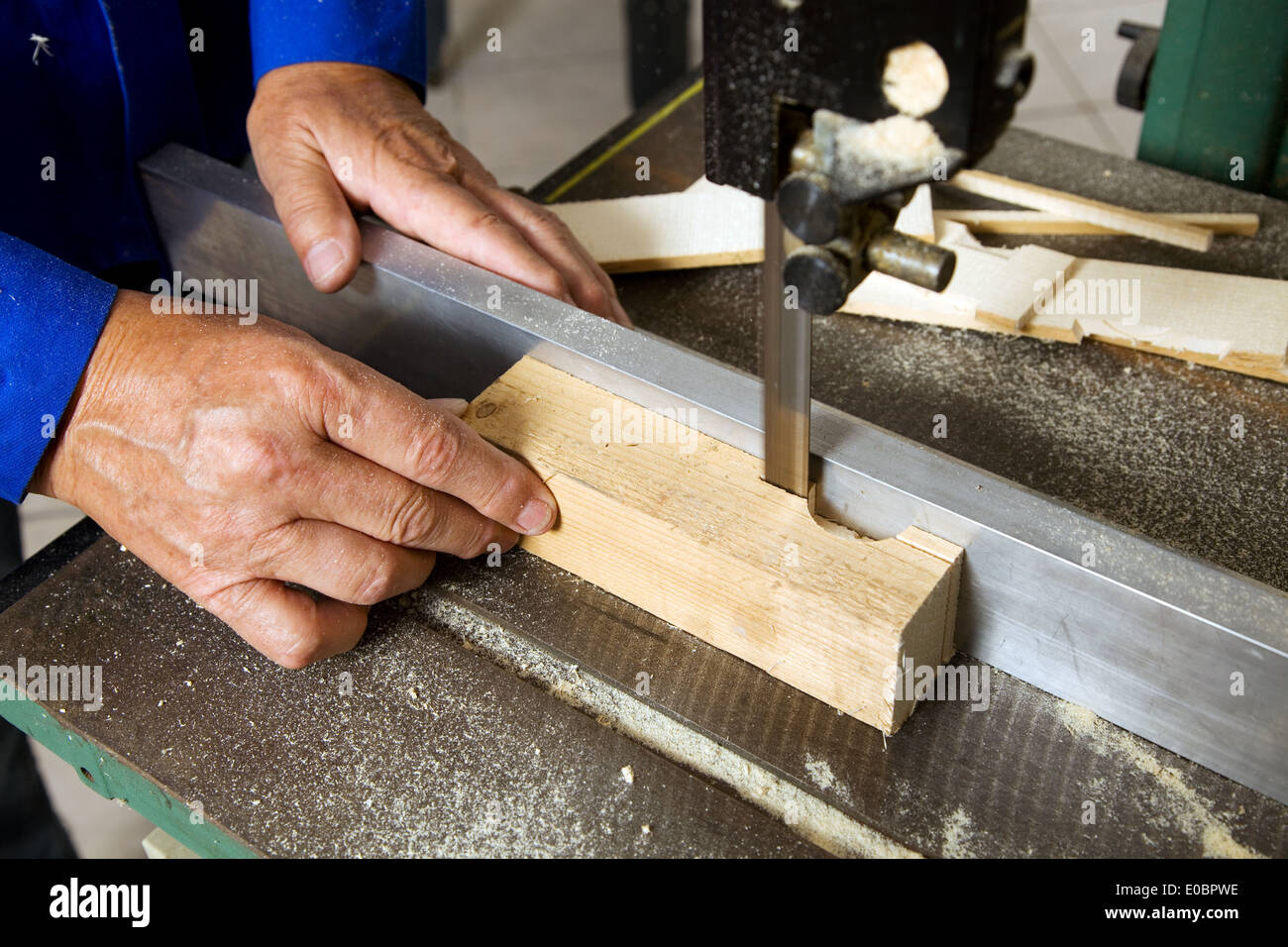 An older carpenter in a belt saw in a carpenter's workshop, Ein aelterer Schreiner an einer Bandsaege in einer Tischlerei Stock Photo