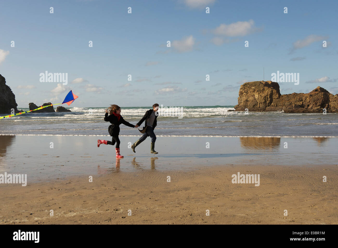Young Romantic Couple flying kite on a Beautiful Cornish Beach Stock Photo