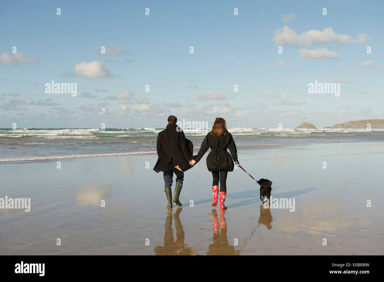 Young Romantic Couple walking their dog on a Beautiful Cornish Beach Stock Photo