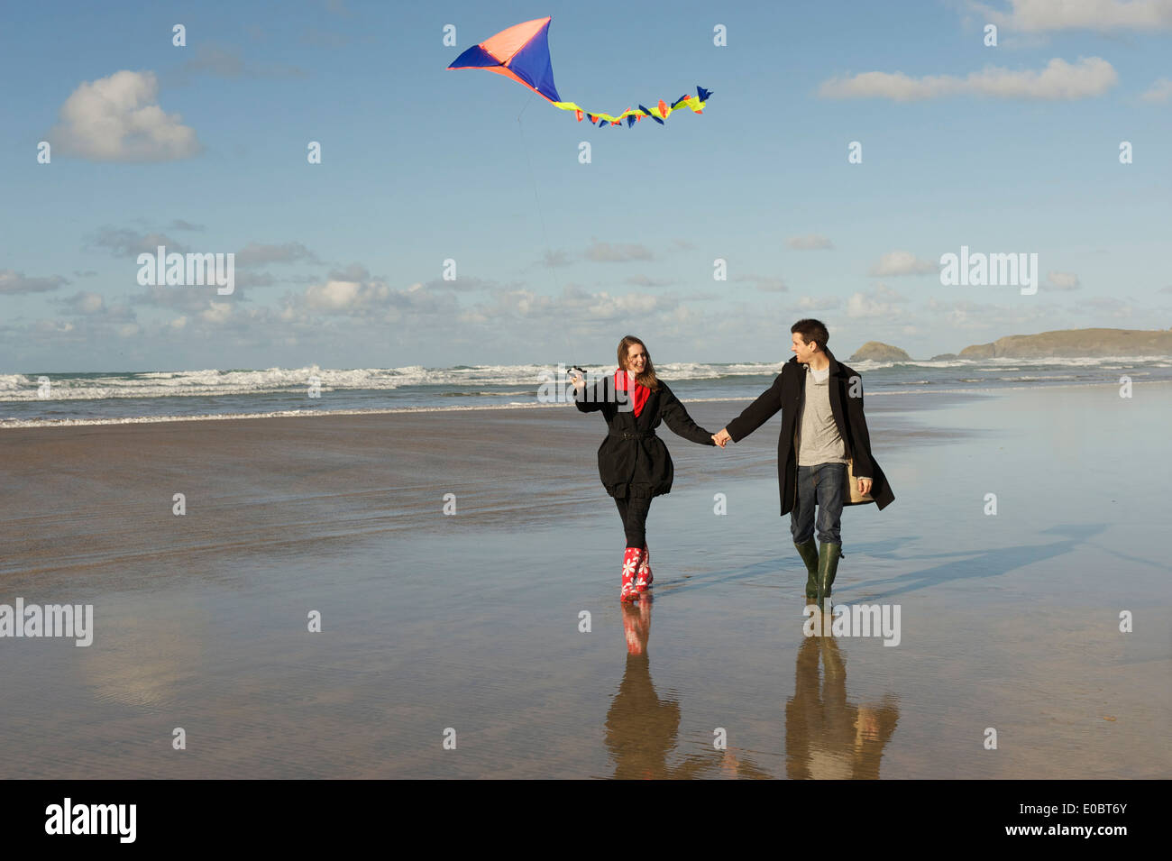 Couple on a beach flying a kite in late evening light Stock Photo - Alamy