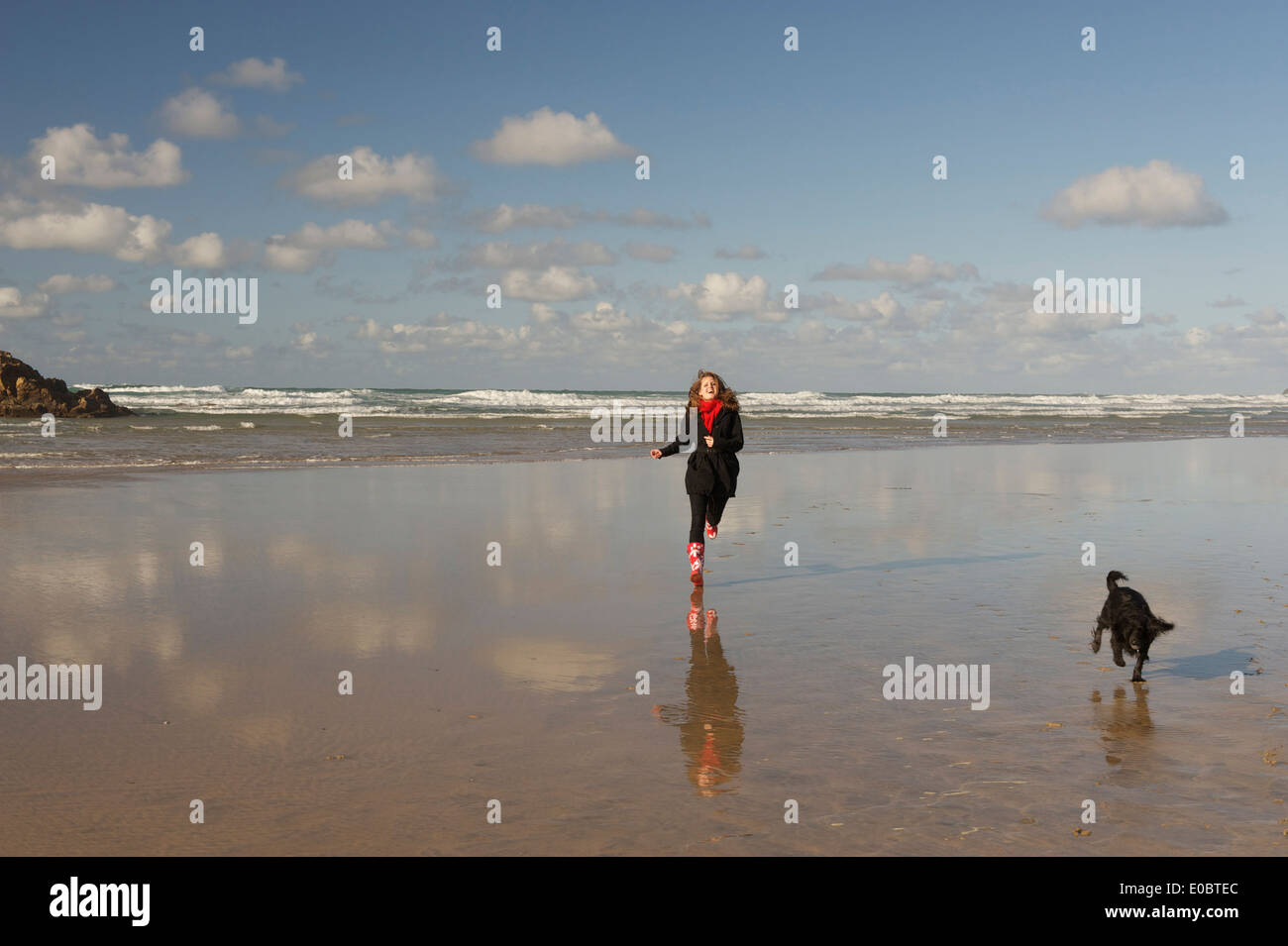 Young Woman running with dog on beautiful Cornish Beach Stock Photo