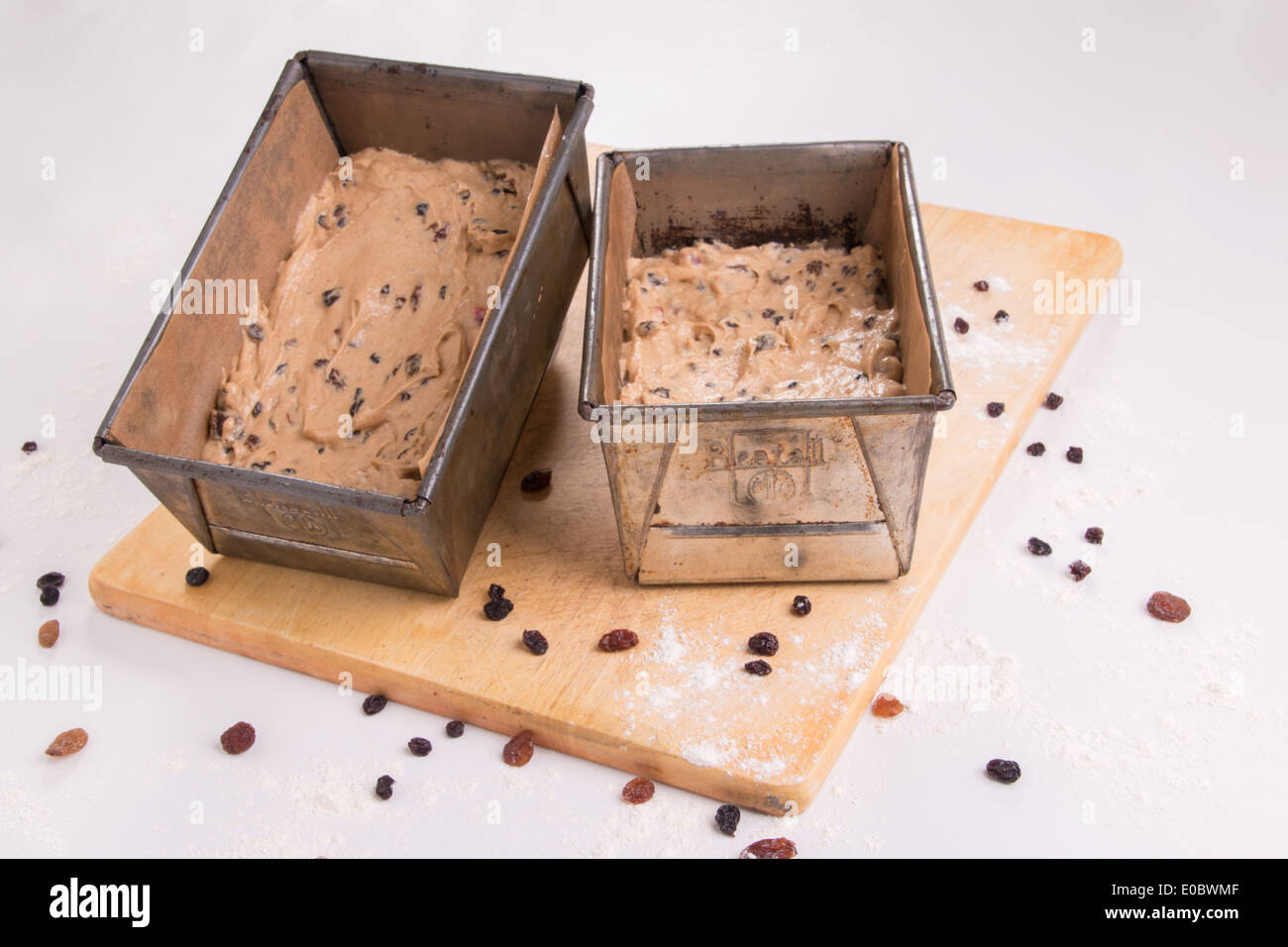 Traditional Fruit loaves in tins/pans ready to cook/bake set on a wooden board with dried fruit scatter ( 1 of 19) Stock Photo