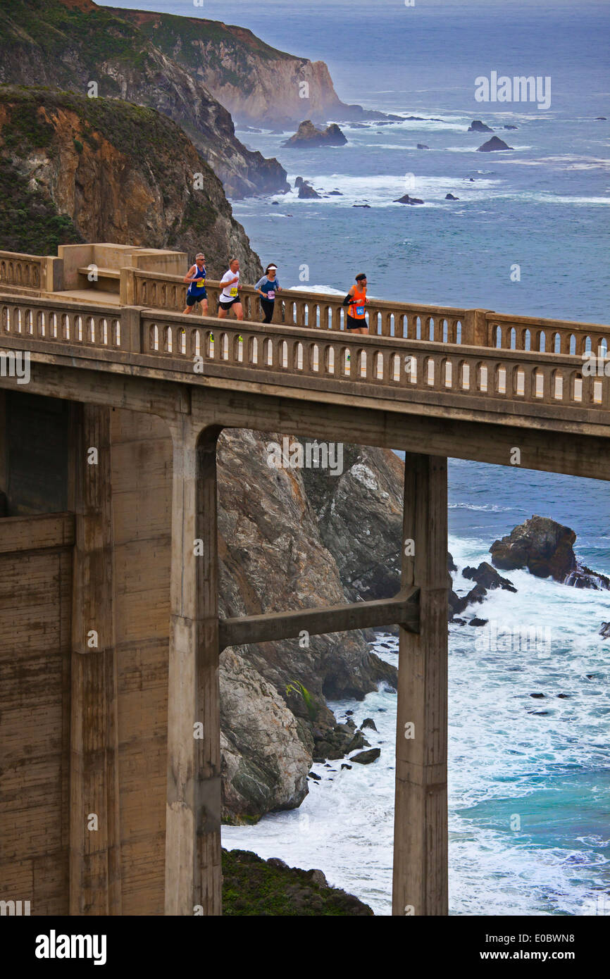 Runners cross Bixby Bridge on Highway 1 which is the half way point of the 2014 Big Sur Marathon - BIG SUR, CALIFORNIA Stock Photo