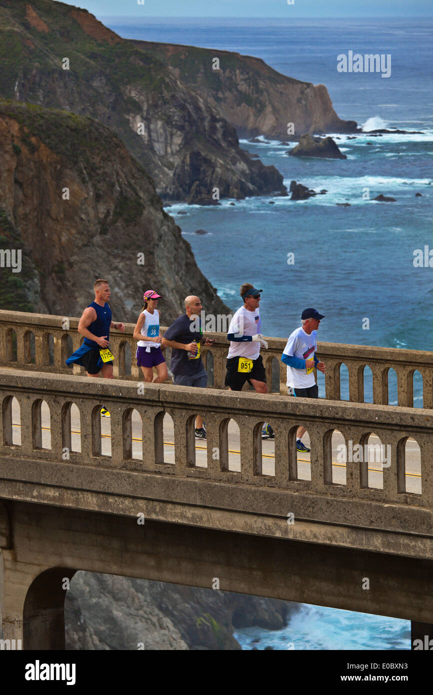 Runners cross Bixby Bridge on Highway 1 which is the half way point of the 2014 Big Sur Marathon - BIG SUR, CALIFORNIA Stock Photo