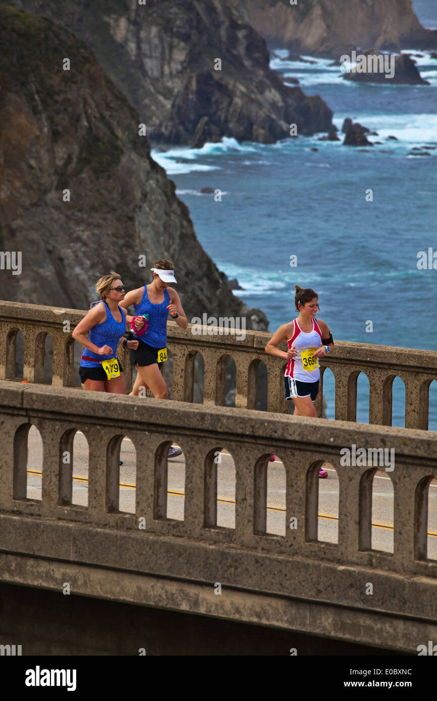 Runners cross Bixby Bridge on Highway 1 which is the half way point of the 2014 Big Sur Marathon - BIG SUR, CALIFORNIA Stock Photo