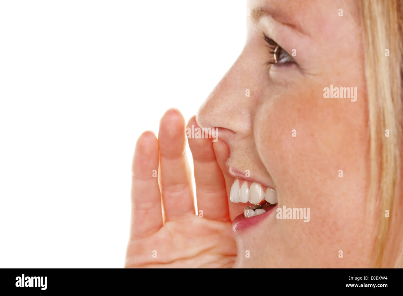 A young woman keeps the hand before the mouth and tells a secret, Eine junge Frau haelt sich die Hand vor den Mund und erzaehlt Stock Photo