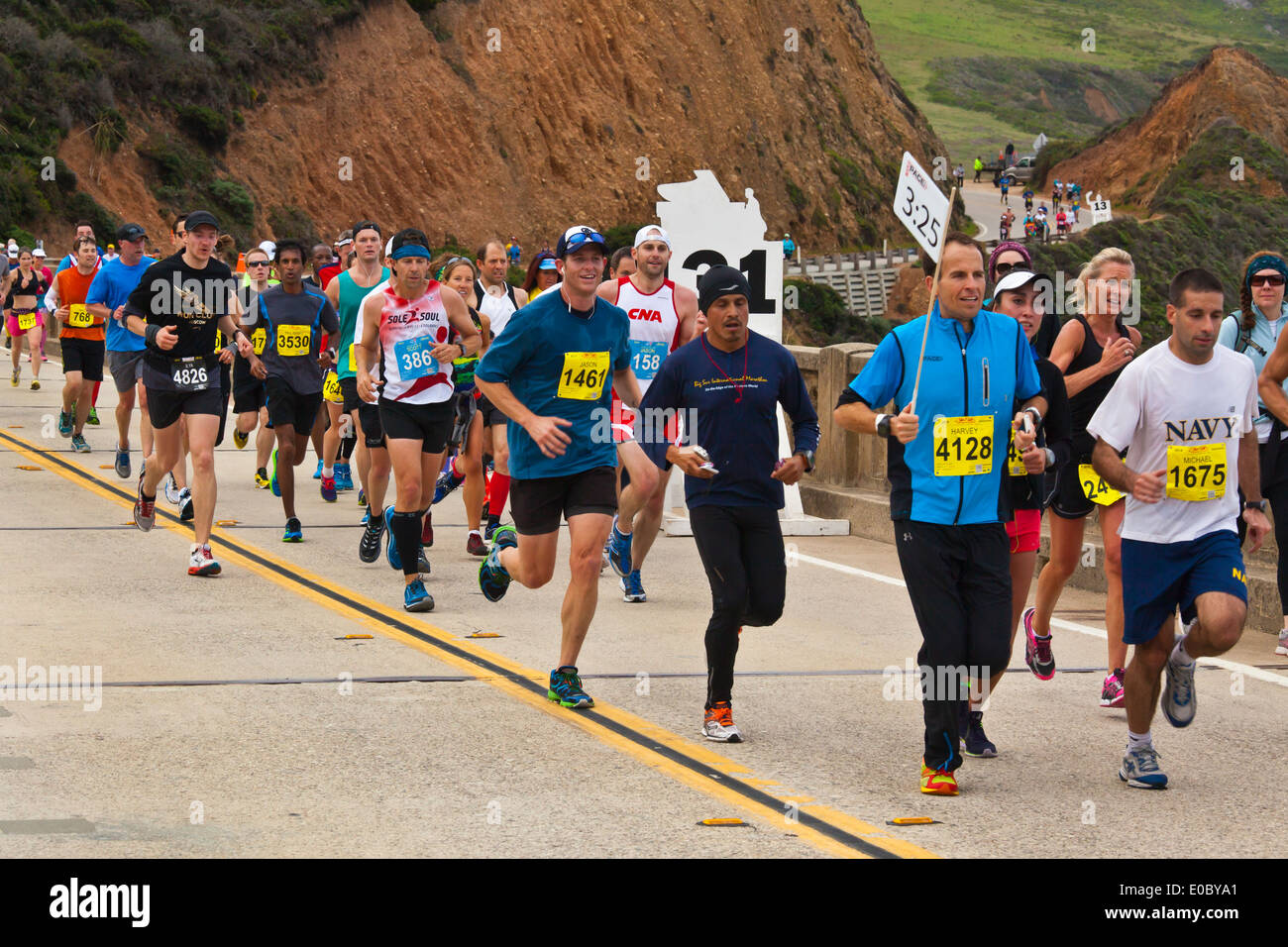 Runners cross Bixby Bridge on Highway 1 which is the half way point of the 2014 Big Sur Marathon - BIG SUR, CALIFORNIA Stock Photo