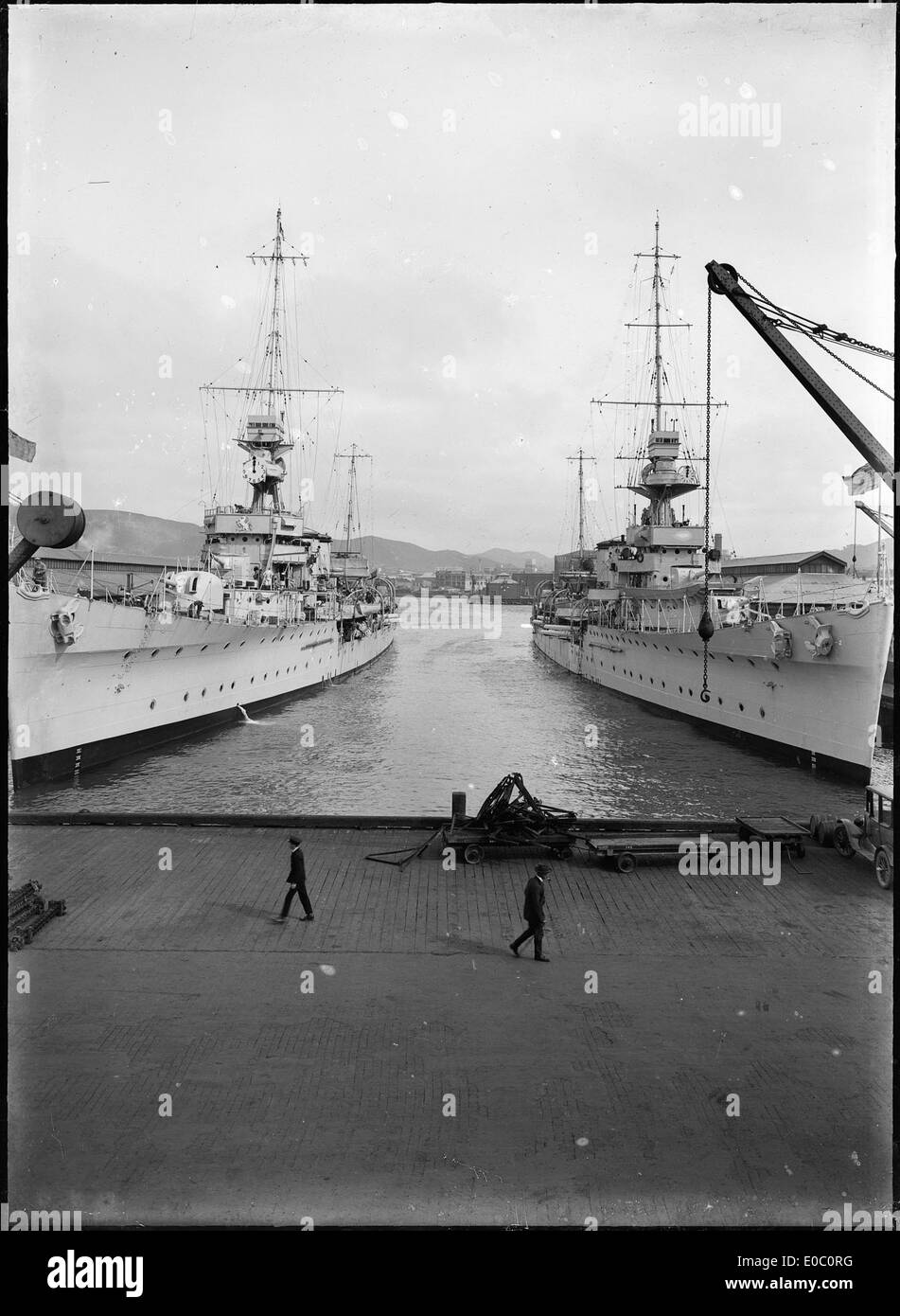 A historical photograph showing the warships HMS Diomede and HMS Dunedin berthed in Wellington, New Zealand, around 1928. This image captures the naval strength of the Royal Navy during the interwar period. Stock Photo