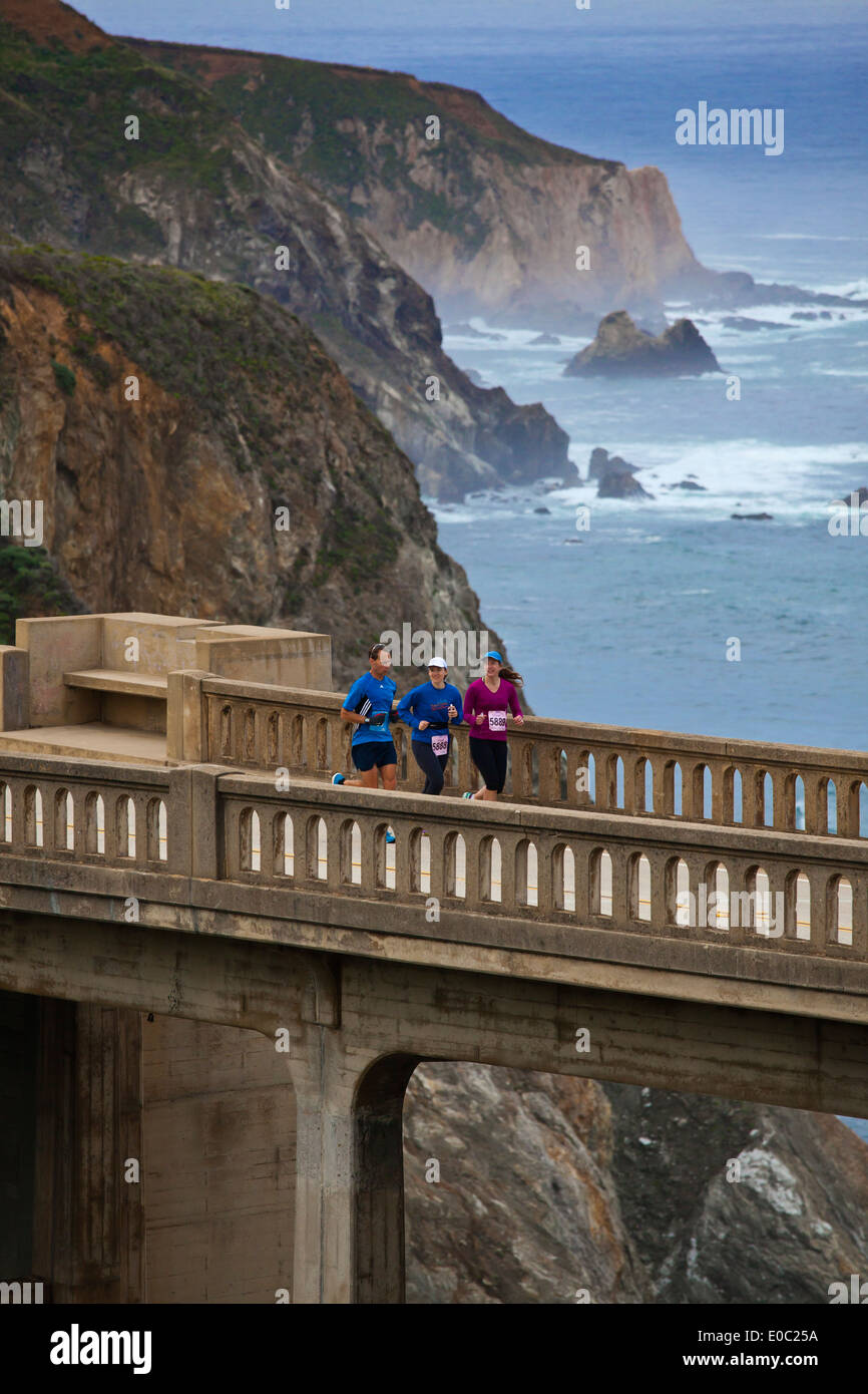 Runners cross Bixby Bridge on Highway 1 which is the half way point of the 2014 Big Sur Marathon - BIG SUR, CALIFORNIA Stock Photo