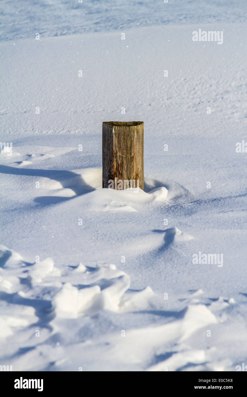 Fence post, in rural Alberta, almost buried by snow, showing drifting results. Stock Photo