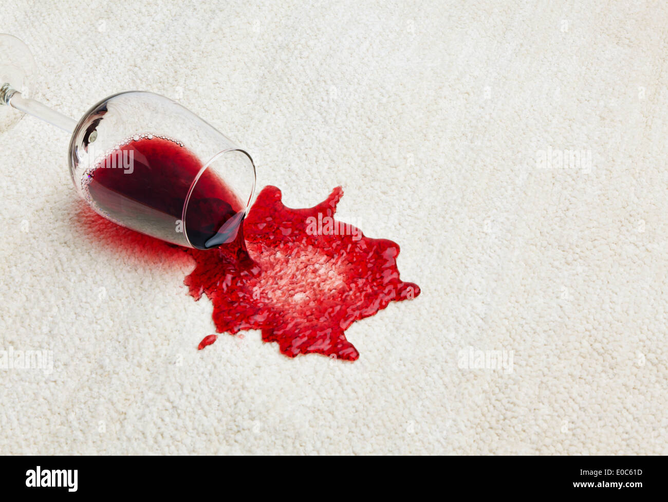 Red wine is tipped out on a carpet. Umgeleertes glass, Roter Wein wird auf einem Teppich ausgeschuettet. Umgeleertes Glas Stock Photo